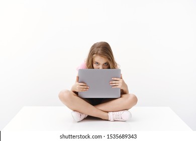 Cute Cheerful Charismatic Blond Young Kid Little Girl Student, Sit On Floor, Hiding Face Behind Laptop Screen, Stare Camera Bored, Peeking, Unwilling Do Homework Wanna Watch Cartoons, Play Computer