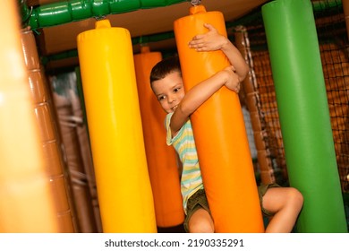 A Cute Cheerful Child On A Colorful Obstacle Course In A Children's Play Center.