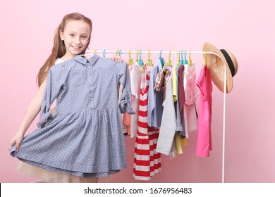 Cute cheerful little girl chooses clothes with floor hangers. Children's clothing, children's shopping. Fashionable clothes for children.
 - Powered by Shutterstock