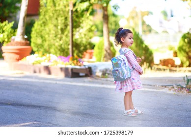 Cute child back to preschool with holographic backpack. Toddler kid first day at kindergarten. Happy sweet girl going back to school after covid-19, coronavirus quarantine and lockdown.