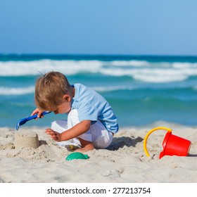 Cute Child Boy Building Sandcastle On The Beach