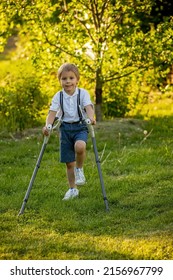 Cute child, boy, walking with crutches in a garden, having his leg injured