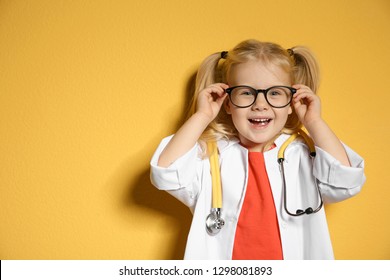 Cute Child In Doctor Coat With Stethoscope On Color Background. Space For Text