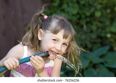 A Cute Child Drinking From A Garden Hose