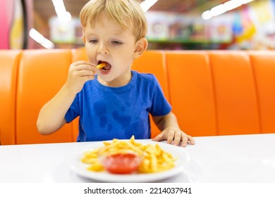 Cute Child Eating French Fries With Sauce At Table In Fast Food Restaurant