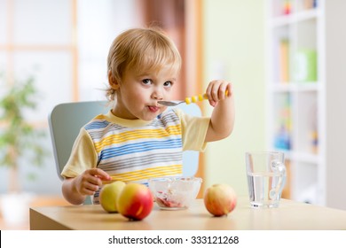 Cute Child Eating Healthy Food With A Spoon At Home