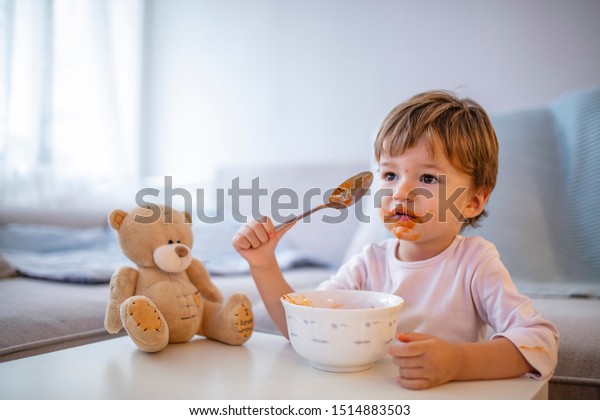 Cute\
child eating healthy food with with the left hand at home. Cute\
child little boy eats healthy food vegetables. It\'s really yummy.\
Kid eating healthy food at home or\
kindergarten