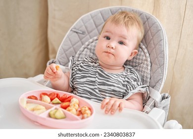 Cute child eats healthy food vegetables and meatballs from dietary meat steamed,. Portraits of a cute 10 months old baby girl. The baby sitting in a special high chair for babies.