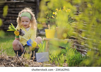 Cute Child Girl Having Fun Playing Little Gardener In Early Spring Garden