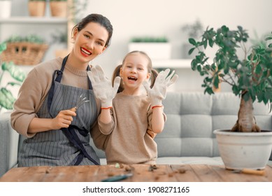 Cute Child Girl Helping Her Mother To Care For Plants. Mom And Her Daughter Engaging In Gardening At Home. Happy Family In Spring Day.