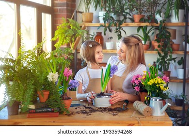 Cute Child Girl Helps Her Mother To Care For Plants. Mom And Her Daughter Engaged In Gardening. Happy Family In Spring Day.