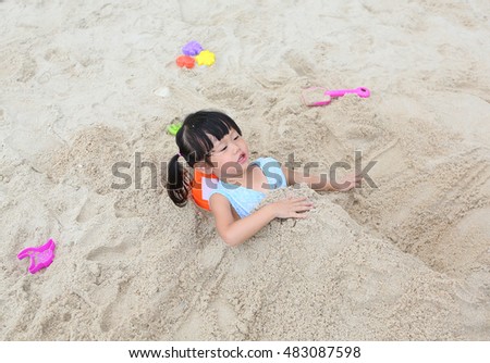 Cute child girl playing sand at the beach