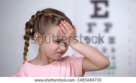 Cute child girl suffering headache, first myopia symptom, loss of eyesight