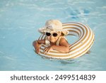 Cute child in a glasses plays in the pool on vacation at the water park