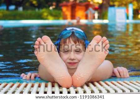 Cute child hanging his feet out of the swimming pool