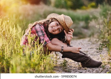 Cute child having fun outdoors, little girl cowboy  park at sunset. Happy baby girl in cowboy hat sits on a meadow. - Powered by Shutterstock