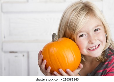 Cute child holding small pumpkin up by her face - Powered by Shutterstock