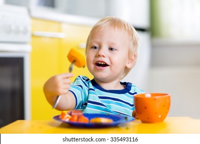 Cute Child Little Boy Eating Healthy Food In Kitchen