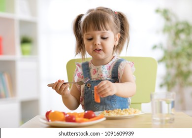 Cute child little girl eating healthy vegetables at home - Shutterstock ID 1091609939