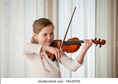 Cute child (little girl) playing violin and exercising at home - Powered by Shutterstock