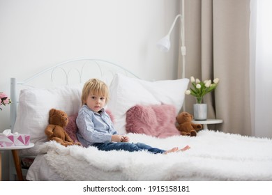 Cute child, lying in bed, reading book at home