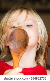 Cute Child With Messy Face Licking Chocolate Covered Spoon