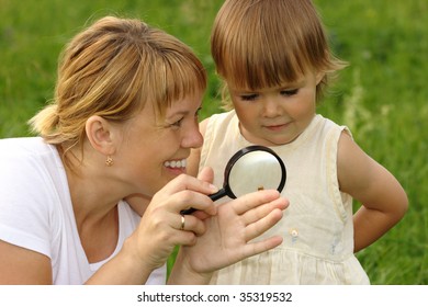 Cute Child With Mother Looking At Little Snail Through Magnifying Glass