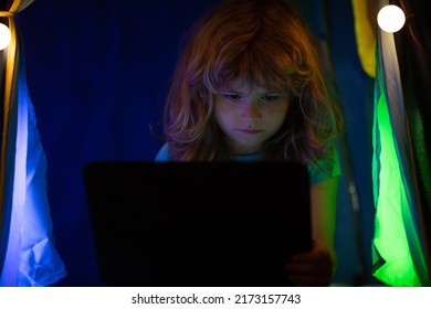 Cute Child Playing And Surfing Online Late At Night. Child Addicted To Internet Games And Social Media Cant Sleep. Digital Technology In Childhood And Internet Addiction.