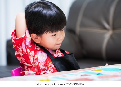 Cute Child Is Reaching For Her Back Scratching Her Back Due To Itching From A Label Attached To Her Clothes. Little Girl Wearing A Red Shirt And Black Apron.