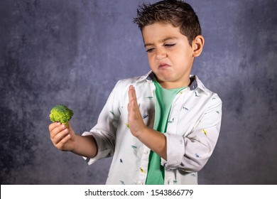 Cute Child Rejecting Broccoli Isolated In Blue