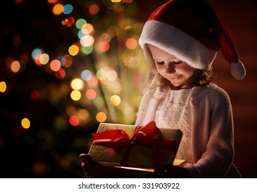 Cute Child In Santa Cap Opening Box With Christmas Gift