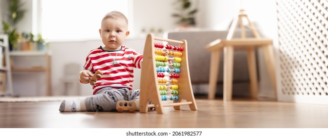 Kleines Kind, das im Zimmer auf dem Boden sitzt und mit Spielzeug spielt.