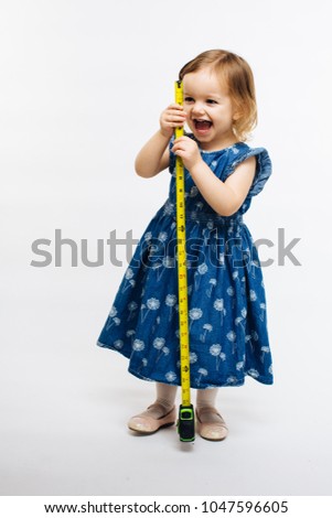 Cute child smiling and holding a measuring tape, they grow fast