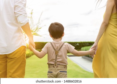Niño o hijo guapo caminando con sus padres. Padre y madre le dan la mano al niño con amor y felicidad por la mañana con aire fresco. Son una familia feliz. Papá, hijo de mamá, pasa tiempo juntos