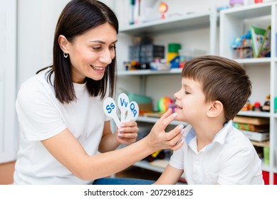 A cute child with a speech therapist is taught to pronounce the letters, words and sounds correctly.