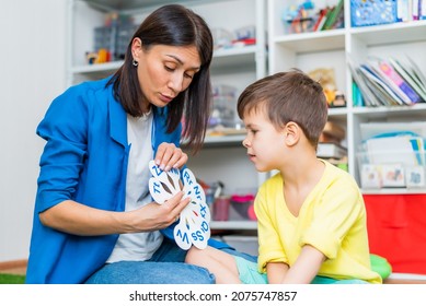 A cute child with a speech therapist is taught to pronounce the letters, words and sounds correctly.