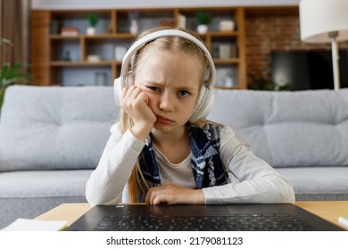 Cute Child Studying Remotely At Home Using Laptop. Tired Primary Schoolgirl Falling Asleep During An Online Lesson With Teacher. Distance Learning Is Boring And Uninteresting. Web Cam View