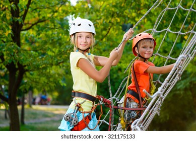 Cute children. Boy and girl climbing in a rope playground structure at adventure park - Powered by Shutterstock