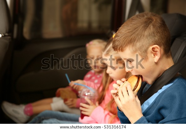 Cute children eating in a\
car