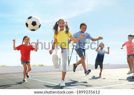Cute children playing soccer outdoors on sunny day. Summer camp