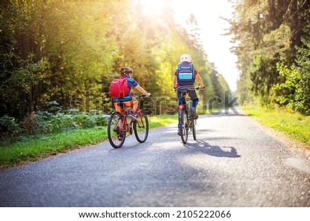 Cute children riding on bicycles on asphalt road in summer. Concept of hiking and friendship.