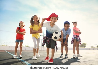 Cute children with soccer ball at sports court on sunny day. Summer camp
