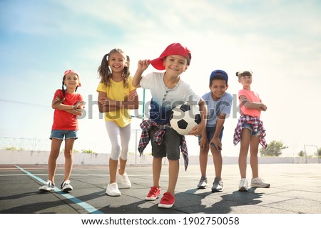 Cute children with soccer ball at sports court on sunny day. Summer camp