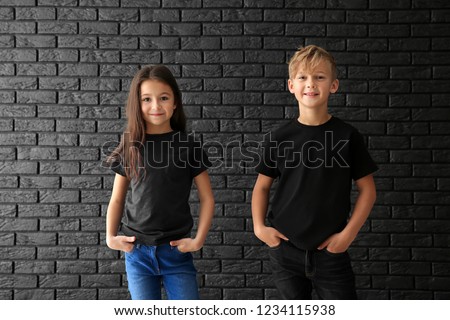 Cute children in t-shirts against dark brick wall