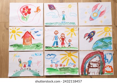 Cute children's drawings on wooden background, flat lay - Powered by Shutterstock