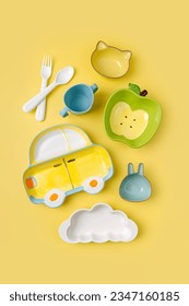 Cute children's plates and dishes shape of a car, clouds and fruits on yellow background. Creative serving for baby. Concept of kids menu, nutrition and feeding. 
