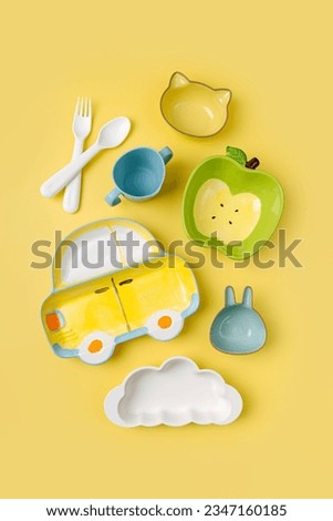 Cute children's plates and dishes shape of a car, clouds and fruits on yellow background. Creative serving for baby. Concept of kids menu, nutrition and feeding. 