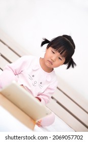 Cute Chinese Little Girl Watching Ipad In Bed