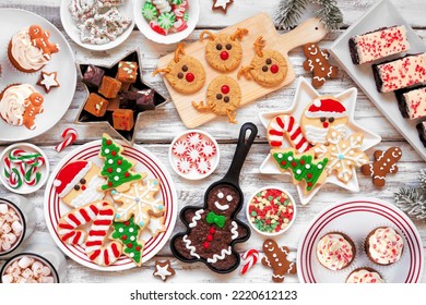 Cute Christmas Sweets And Cookie Table Scene. Top Down View Over A Rustic White Wood Background. Fun Holiday Baking Concept.