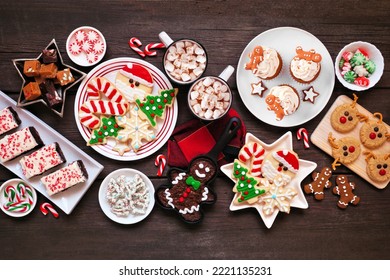 Cute Christmas Sweets And Cookie Table Scene. Top Down View On A Rustic Dark Wood Background. Fun Holiday Baking Concept.